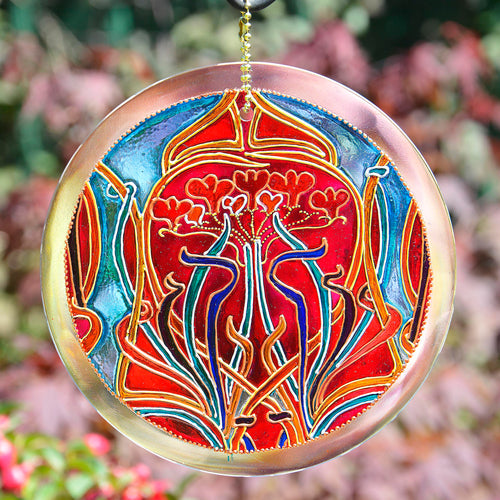 A glowing red heart surrounded by flowing blue ribbons on an Art Nouveau style stained glass suncatcher by Ornately Lanterns