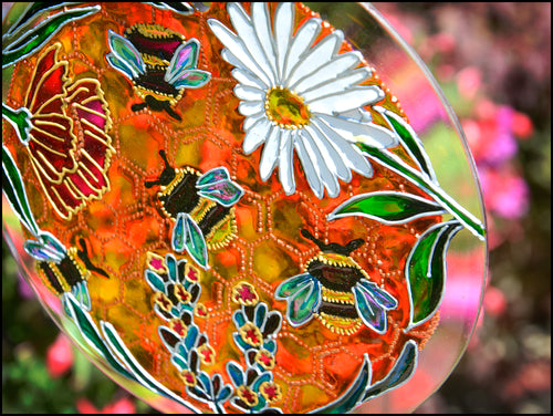 Hand painted bumble bees crawl across the stained glass honeycomb on this hanging floral suncatcher by Ornately Lanterns