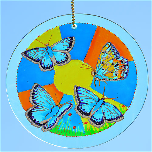 A hanging stained glass suncatcher by Ornately Lanterns featuring four brilliant blue Chalk Hill butterflies in the sunshine