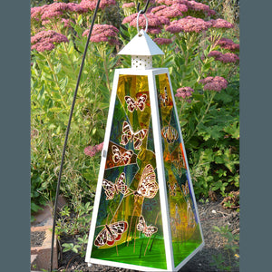 A shabby chic stained glass candle lantern in cream with colourful butterflies in sunshine hand painted on all four panels