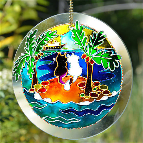 Hanging stained glass suncatcher, hand painted with a cat couple on a desert island looking out to a big boat on the ocean