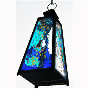 A stained glass candle lantern hand painted with a cat couple sitting on the moon amongst the stars in a rich blue night sky