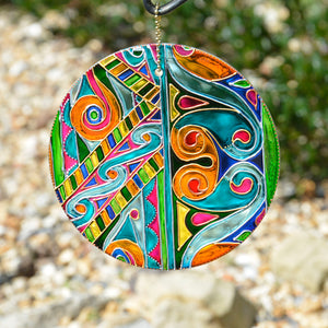 A hanging stained glass suncatcher by Ornately Lanterns hand painted with a Celtic Knots design in soft pastel colours
