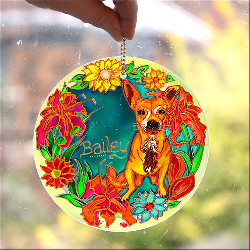 A hanging pet memorial suncatcher, bright in the sun, is personalised with Bailey the chihuahua, surrounded by radiant flowers