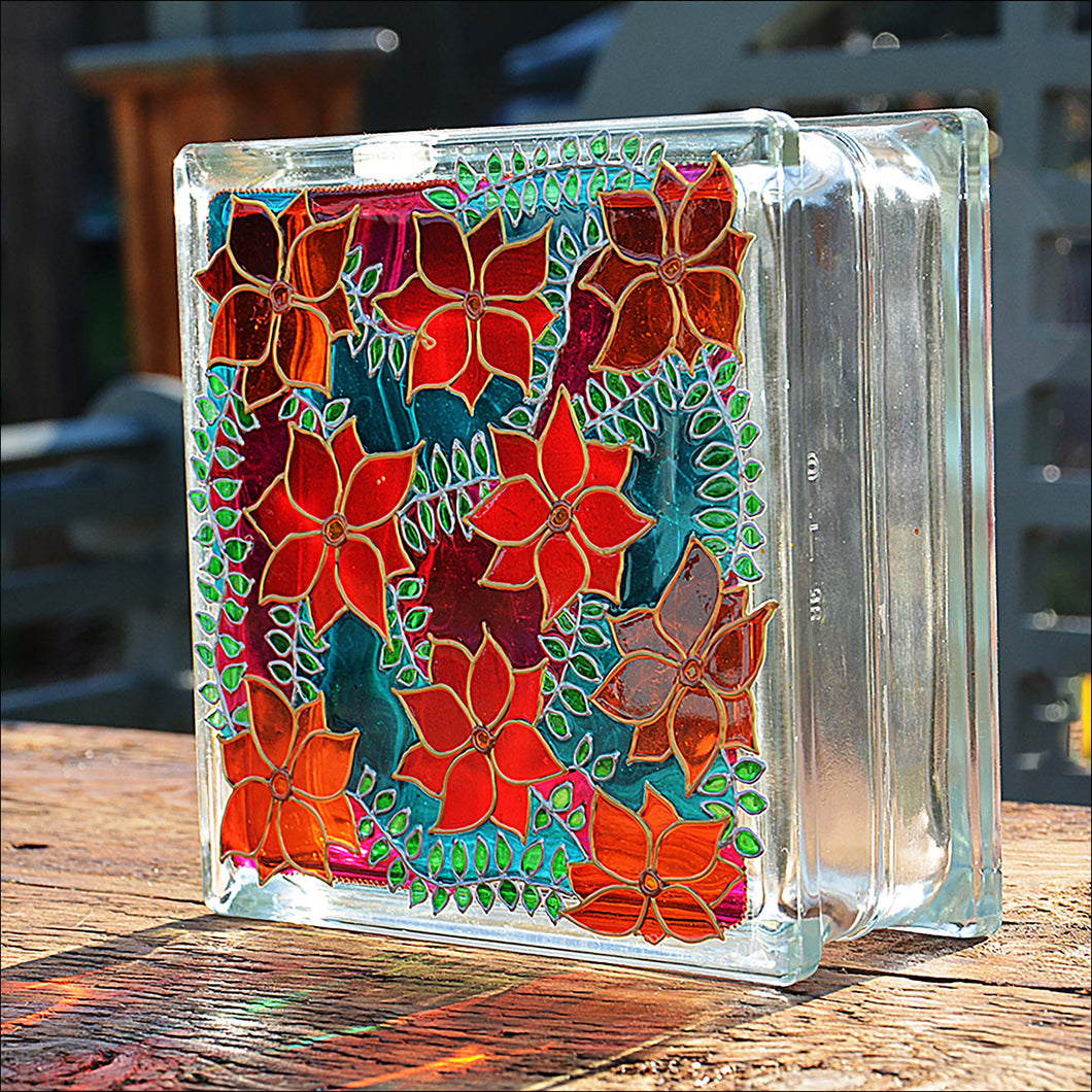 A large stained glass square block, hand painted with beautiful clematis flowers in vibrant red, orange, pink and turquoise