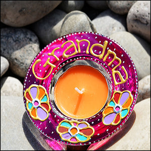 A stained glass tealight candle holder painted bright pink with colourful daisy flowers and personalised in gold for Grandma