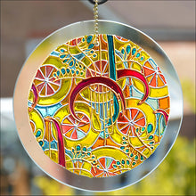 A stained glass suncatcher original painted with swirling abstract shapes in radiant candy colours – yellow, gold and pink