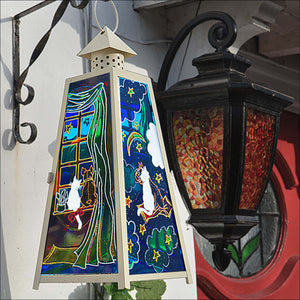 A stain glass candle lantern hanging by the front door – a French bulldog & his cat friend hand painted in jewel like colour
