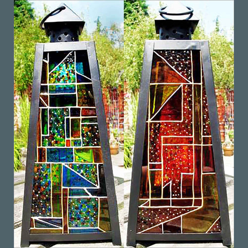 A pair of garden lanterns, both decorated with colourful stained glass patterns in a Mondrian style, one in blues, one reds