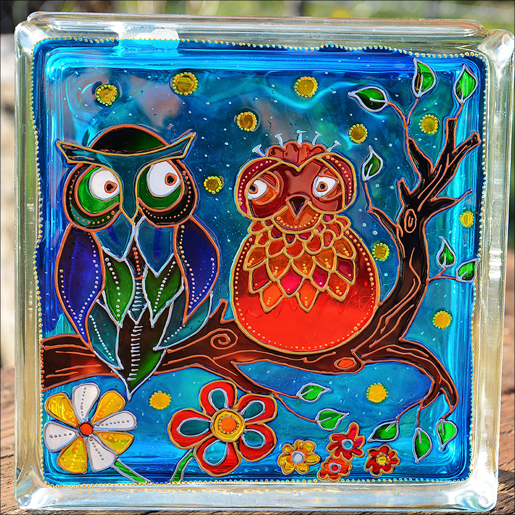 A stained glass block night light or suncatcher painted with a colourful owl couple sitting on a branch against a night sky