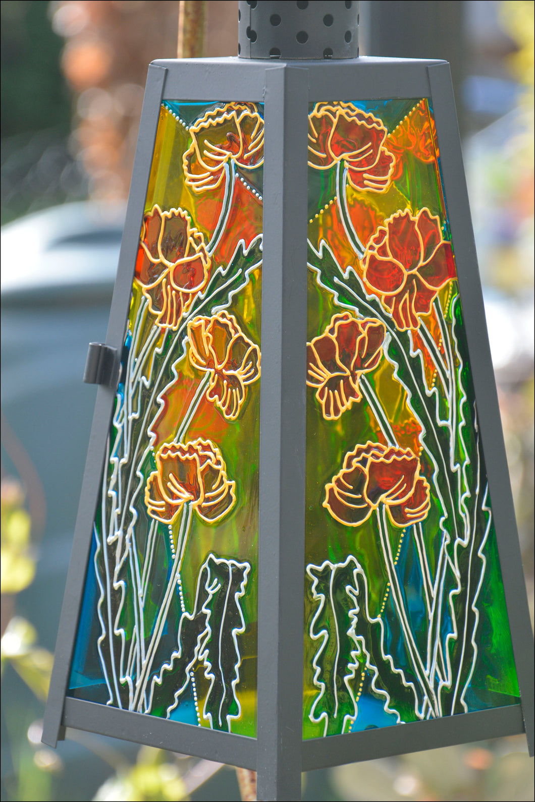 Red & gold California poppies are hand painted in sunshine on panels of a stained glass candle lantern by Ornately Lanterns