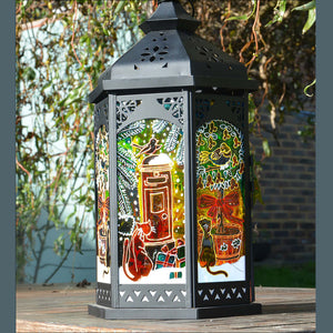 A Christmas candle lantern patterned with festive stained glass cats at a snowy post box and with a partridge in a pear tree