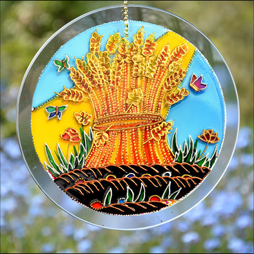 Autumn sunshine falls across a golden wheat sheaf on this stained glass suncatcher - a colourful Harvest & Thanksgiving image